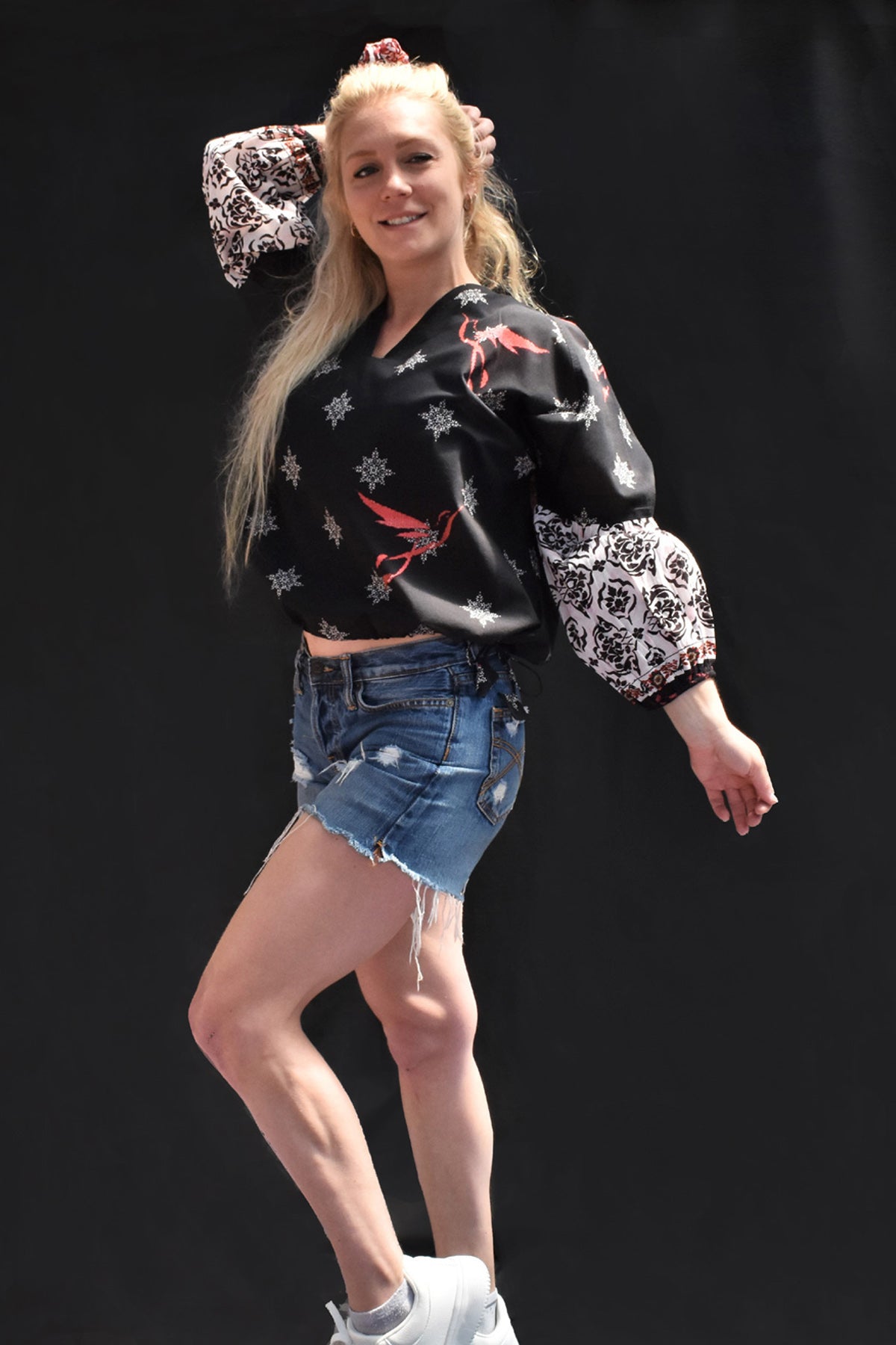 ORA PRINTED COTTON TOP - black printed v neck top with white printed motifs, sleeves are billowy in white with black print. Bright pink bird motif on front and back looks awesome. ties at the bottom and oversized fit. looks great worn as cropped length paired with shorts in this front view image.
